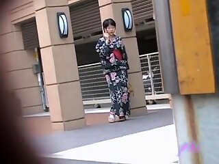 Svarthårig liten geisha blinkar med brösten när någon drar hennes outfit